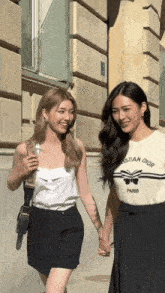 two women holding hands one wearing a christian dior paris shirt
