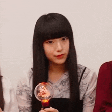 a young woman with long black hair is holding a light bulb .