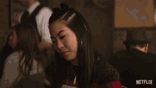 a woman is sitting at a table with a netflix logo in the background