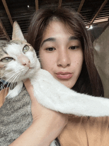 a woman holds a cat in her arms and the cat looks at the camera