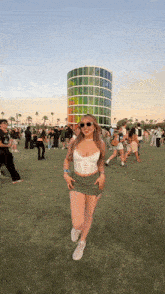a woman wearing sunglasses and a corset is standing in front of a rainbow colored tower