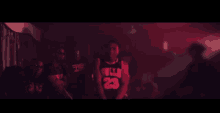 a man in a chicago bulls jersey is standing in a dark room with a crowd behind him .