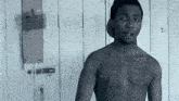 a shirtless man with a tattoo on his chest stands in front of a wall