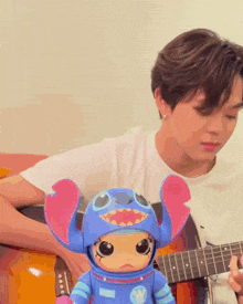 a man is playing a guitar next to a stitch doll
