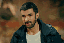 a man with a beard is wearing a black jacket and a white shirt