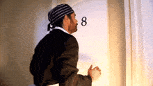 a man wearing a striped hat stands in front of a door with the number 8 on it