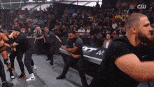 a crowd of people watching a wrestling match with a cw logo in the corner .