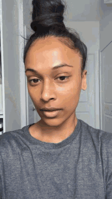 a woman with her hair in a bun is wearing a grey t-shirt