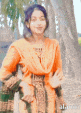 a girl in an orange dress is standing in front of a tree and the word alamin is on the bottom