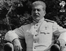 a man in a white uniform is sitting in a chair with his arm resting on the arm of the chair