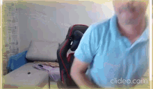 a man in a blue shirt is standing in front of a couch in a room .
