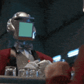 a robot with a green screen on his head is holding a bottle