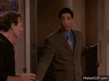 two men are standing next to each other in a doorway talking .