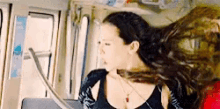 a woman with long hair is sitting on a bus .