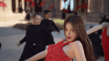 a woman in a red dress is dancing in front of a crowd of people