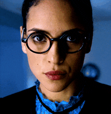 a close up of a woman wearing glasses and a blue sweater