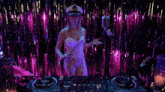 a woman in a captain 's hat is standing in front of a dj 's controller .