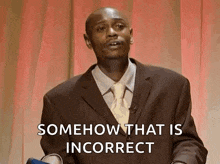 a man in a suit and tie is giving a speech and says somehow that is incorrect .