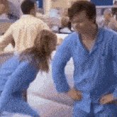 a man and a woman in blue pajamas are dancing in a hospital .
