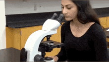 a woman looks through a microscope in a lab
