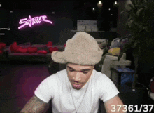 a man wearing a furry hat is sitting in front of a neon sign that says cyberpunk