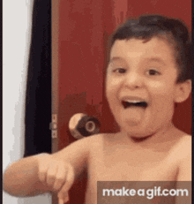 a shirtless young boy is pointing at the camera with his mouth open .