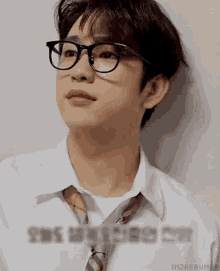a young man wearing glasses and a tie is looking up .
