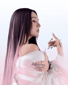 a woman with long black hair and pink streaks is wearing a white off the shoulder top