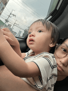 a woman is holding a baby in her arms and the baby is looking at the camera