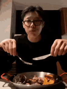 a man wearing glasses is eating from a pan