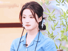 a woman in a blue shirt is looking at the camera with gugubby in the upper right corner