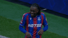 a soccer player wearing a nets jersey is laughing with another player
