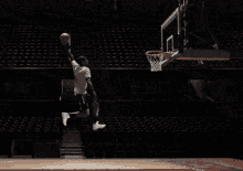 a man in a white shirt is jumping over a basketball net