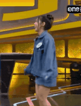 a woman in a denim jacket is standing on a stage .