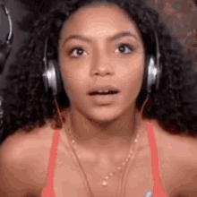 a woman with curly hair is wearing headphones and a necklace .