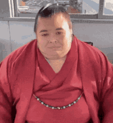 a very fat man wearing a red robe and a necklace