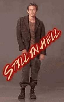 a man in a suit is standing in front of a sign that says still in hell