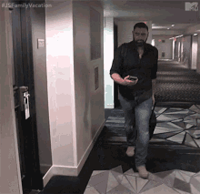 a man walking down a hallway with a suitcase and a cell phone with the hashtag #usefamilyvacation on the bottom