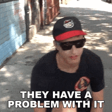 a man wearing a baseball cap and sunglasses says they have a problem with it