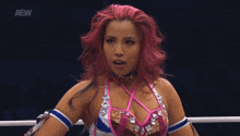 a woman with pink hair is standing in a ring with the aew logo on the bottom right