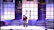 a man is standing on a stage with a ladder behind him .