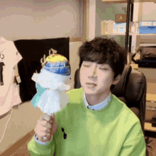 a young man in a green sweater is holding a lollipop with a globe on it