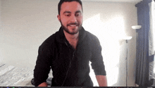 a man with a beard is smiling in front of a computer screen that says 1:00 pm