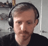 a man with a beard wearing headphones and a black shirt .