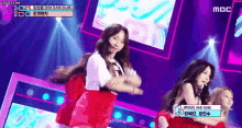 a group of women are dancing on a stage with a sign that says mbc on it