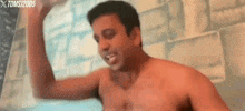 a shirtless man is taking a shower and flexing his muscles