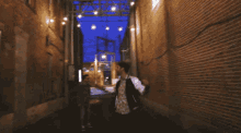 a man in a white jacket stands in an alleyway