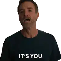 a man in a blue shirt is smiling and says it 's you