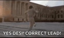 a man is running in front of a building with the words `` yes desi correct lead '' written on it .