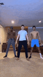 three men are standing next to each other in a living room without shirts on .